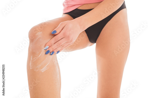 Woman applying body cream on her leg in bedroom, closeup