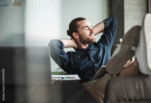 Relaxed smiling businessman sitting in office with closed eyes photo