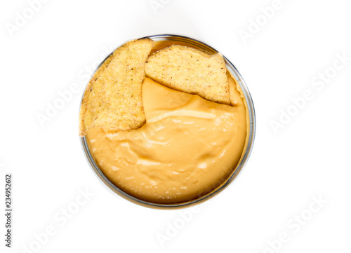 Close up of nachos in a tasty yellow cheddar cheese in a metallic cup, isolated on white. Nacho in cheddar.