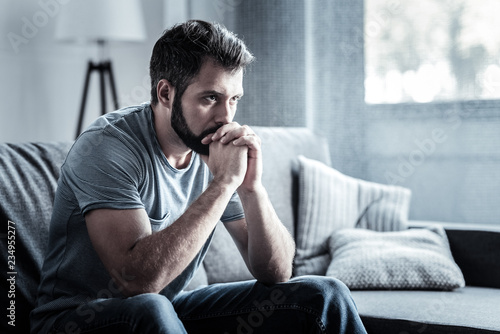 Depressive bearded man being deep in thoughts