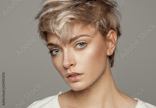 Portrait of young girl with blond short hairstyle looking at camera isolated on gray background with copy space