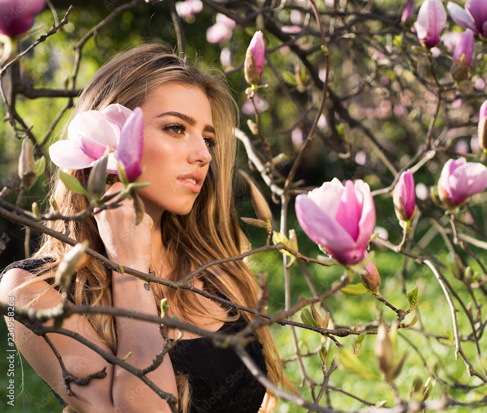 Fototapeta premium Magnolia. Spring girl in blooming garden. Summer girl and sensual moment. Beauty woman outdoors in blooming trees. Beauty girl in flowers.