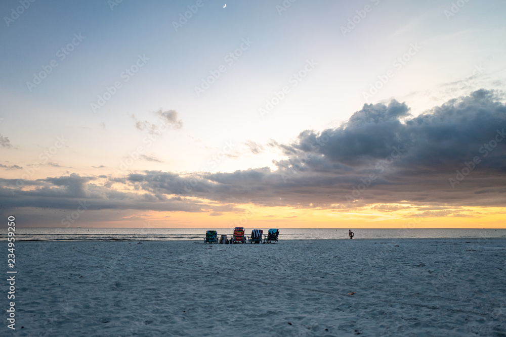 4 empty beach chairs facing the ocean at sunset, fort myers beach 4 empty beach chairs facing the ocean at sunset, fort myers beach