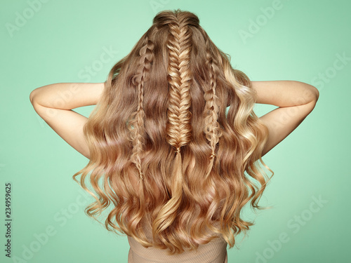 Blonde Girl with Long and Shiny Curly Hair. Beautiful Model Woman with Curly Hairstyle. Care and Beauty Hair Products. Lady with braided hair