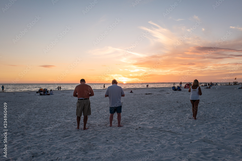 Fototapeta premium two men taking pictures of the sunset over sanibel island