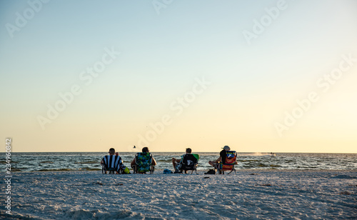 4 people lounging in beach chairs, waiting for sunset in fort myers beach