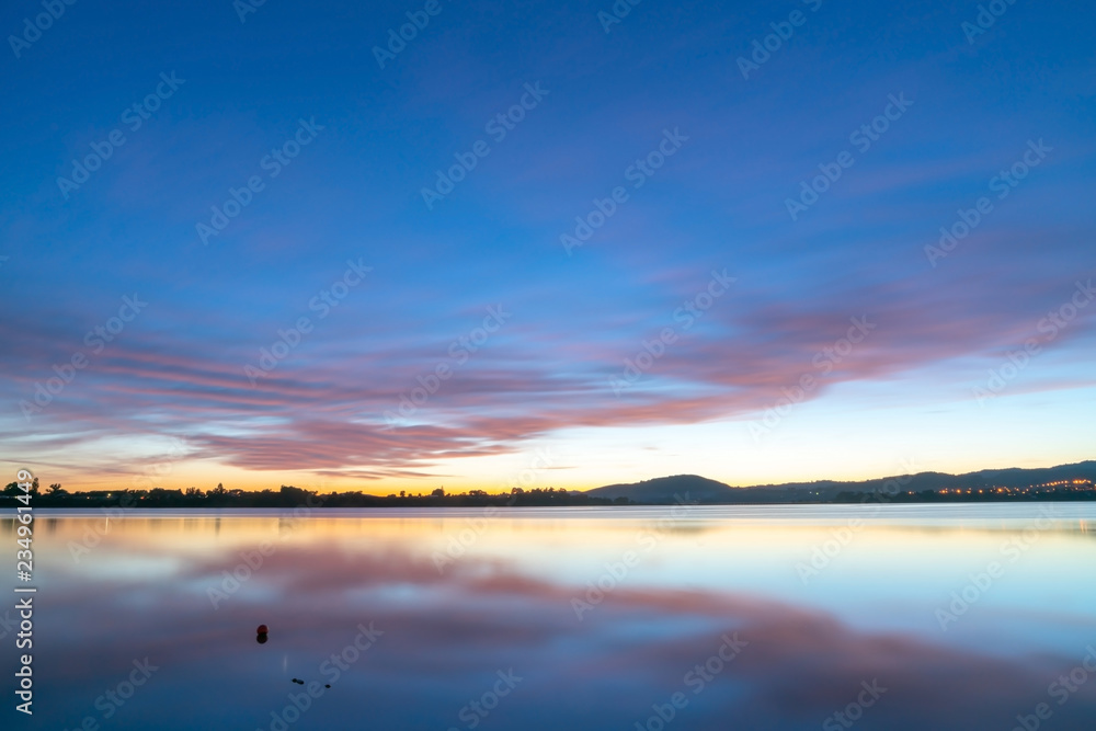 Calming effect of long exposure sunrise over bay in pink and blue hues.