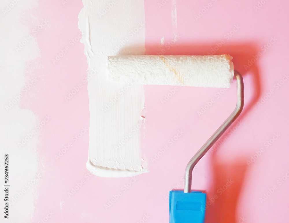 Obraz premium Roller with white paint next to the pink wall