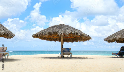 Cabana, parasol. White sand beach. Blue sea water and dramatic clouds. Oranjestad, Aruba. Famous Eagle Beach. 
