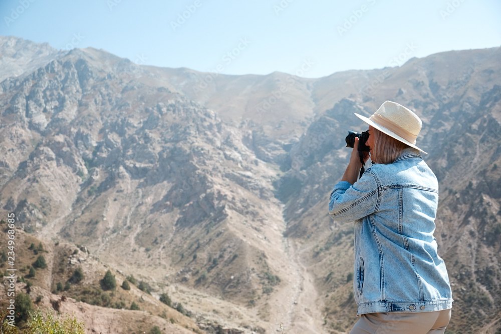 Hiker photographer taking picture of the landscape with mountains