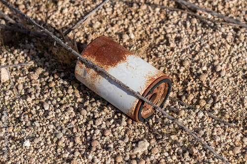 Rusty discarded oil filter in the sand 