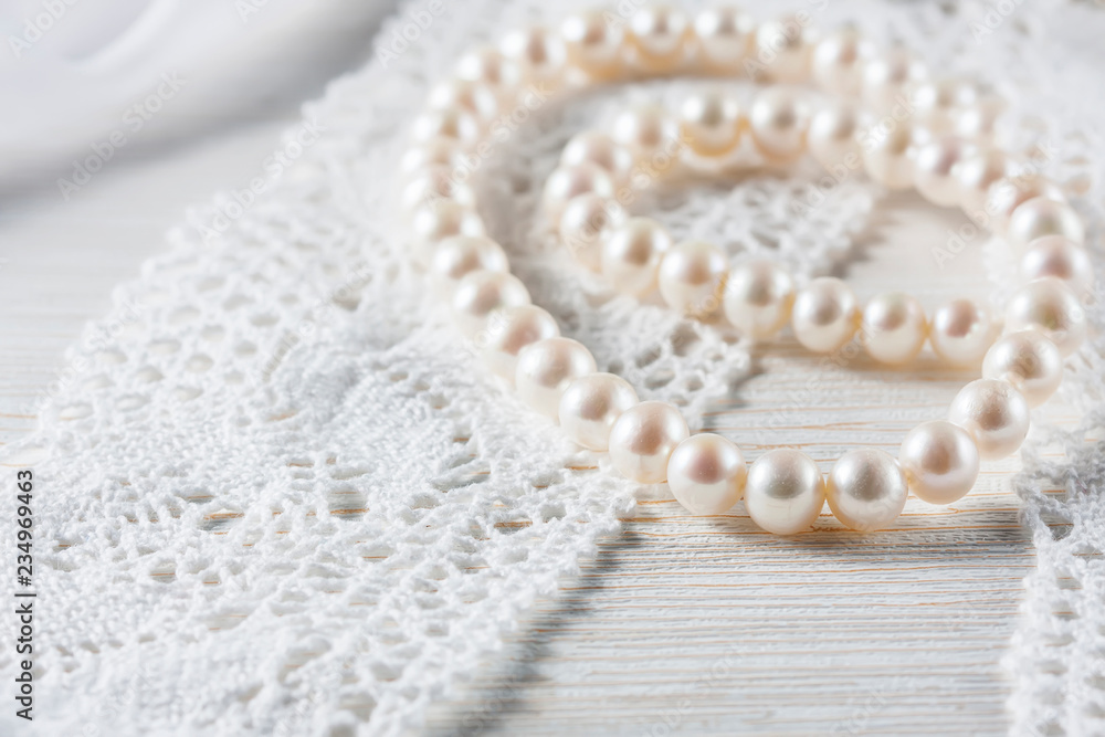 Obraz premium White pearl necklace on handmade lace background.