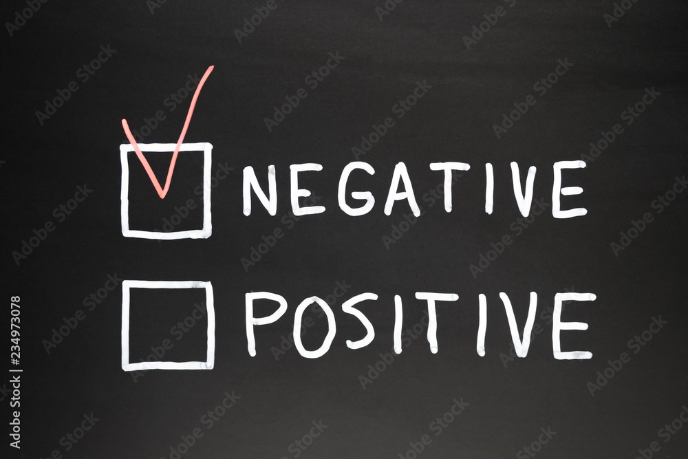 Negative and positive written on a black slate with chalk. In red marked negative box