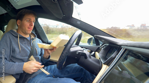 Принти на полотні CLOSE UP: Male driver eating while driving home in a self steering vehicle