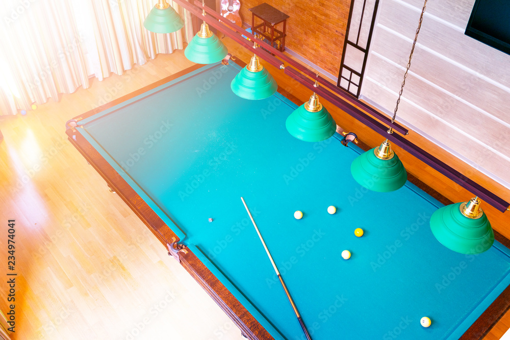 Billiard table close up. Playing billiard. Billiards balls and cue on green billiards table. Billiard sport concept. Pool billiard game. Home interior.