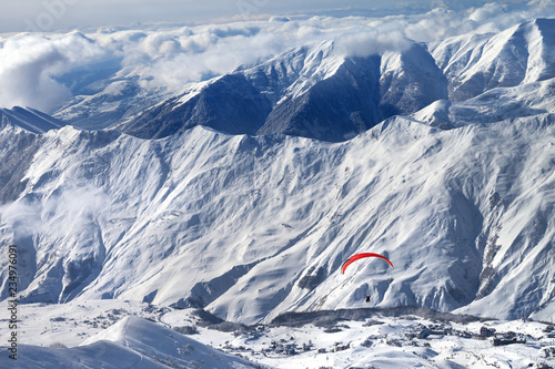 Paragliding at snowy mountains over ski resort and off-piste slope © BSANI
