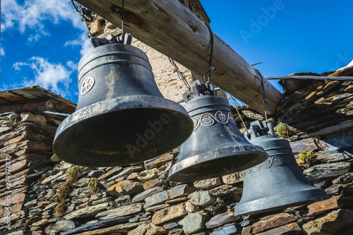 Bells in Lamaria church in Zhibiani - Ushguli community of villages, Upper Svaneti, Georgia, view from below with blue sky background photo