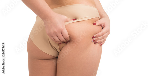 young woman pinching fat on her buttocks on white background