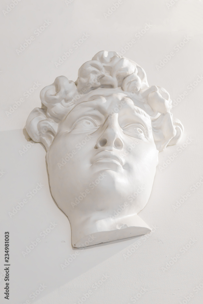 gypsum head of a man on the wall under the light