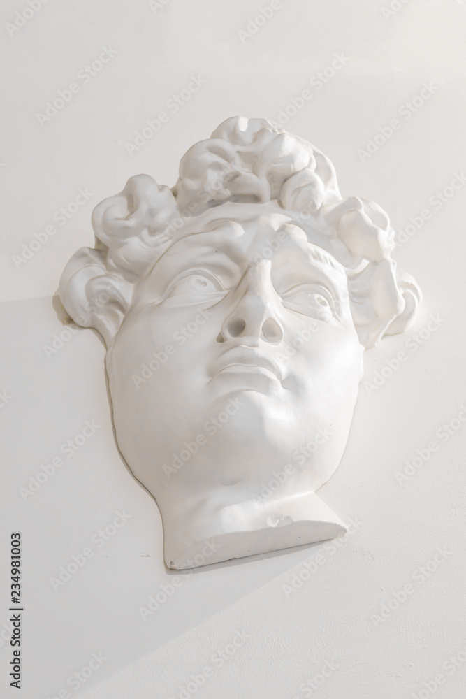 gypsum head of a man on the wall under the light gypsum head of a man on the wall under the light