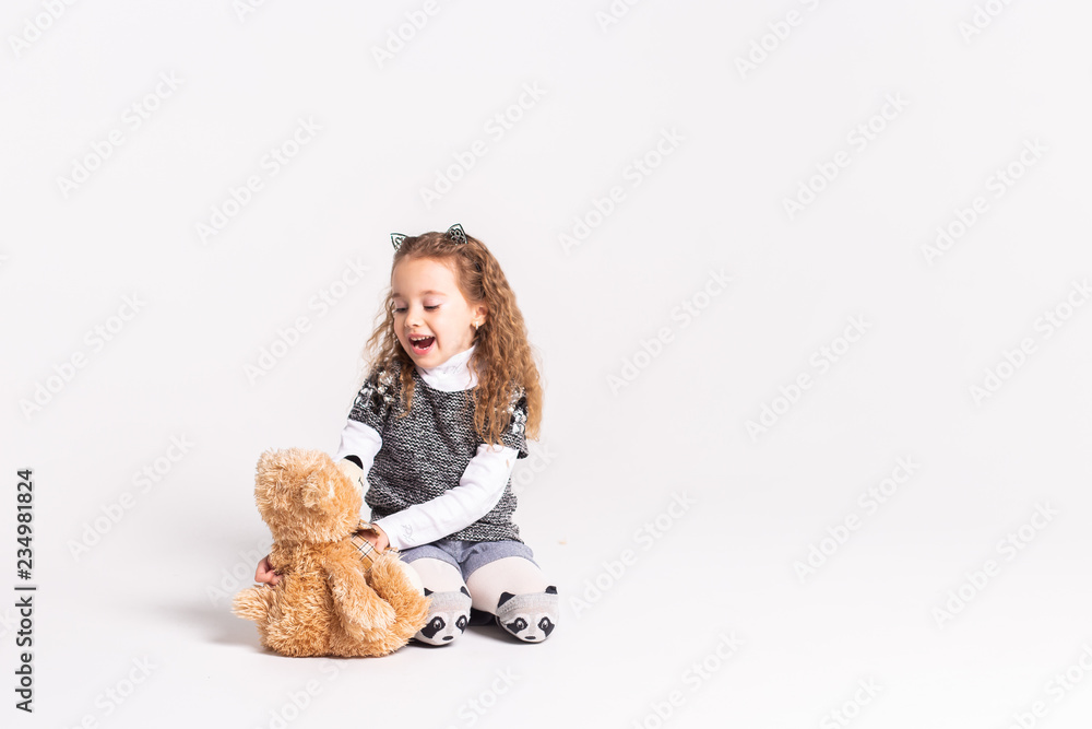 A little girl with a bear standing on a white background A little girl with a bear standing on a white background