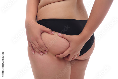  young woman pinching fat on her buttocks on white background