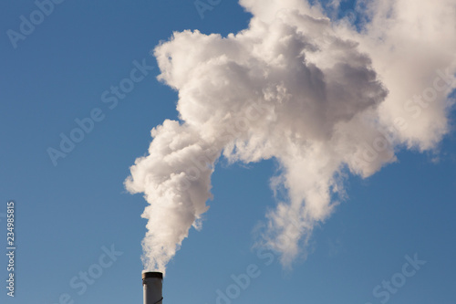 White smoke is coming out of the stack, blue sky background.