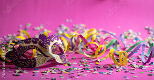 Carnival mask, streamers and confetti on pink background