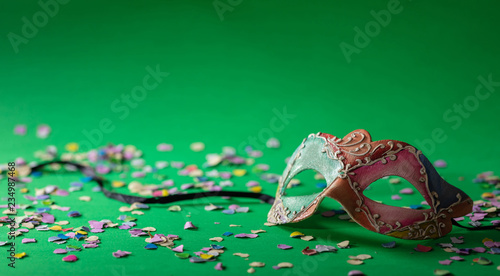 Carnival mask and confetti on green background