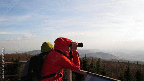 Man in Red Hood in Mountains Looking through Binocular Outdoors