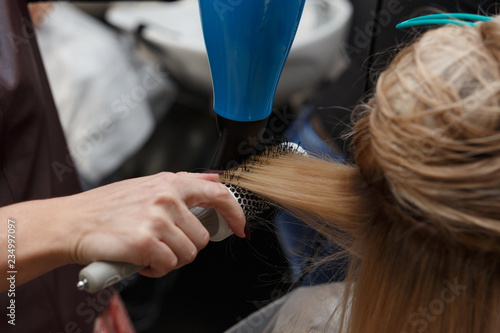 Hairdressers hands drying blond hair