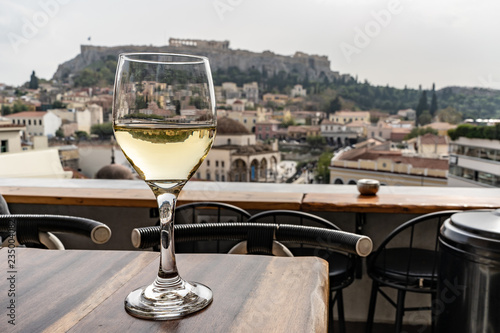 Glass of wine with a view of the Acropolis in Athens, Greece. White wine. Wide angle close up.