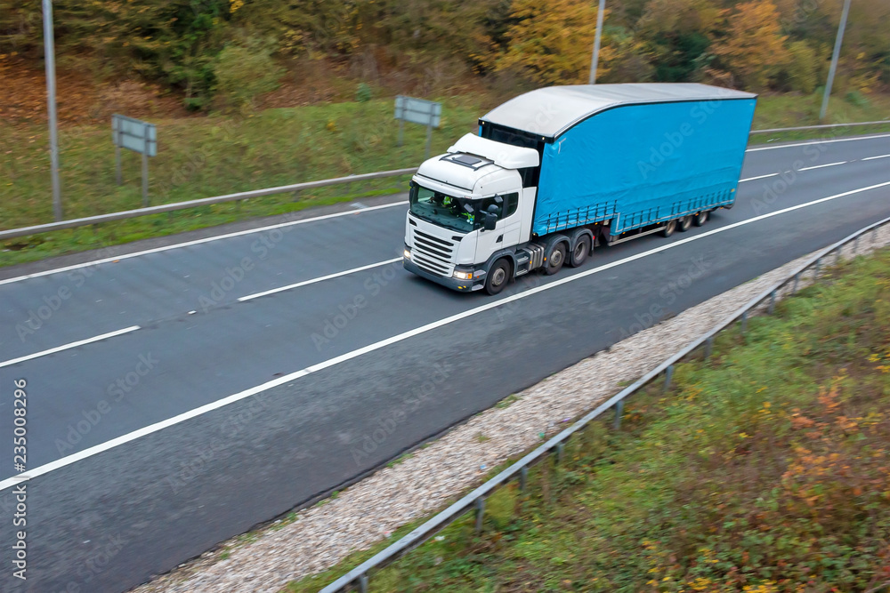 Articulated lorry with blue high double decker trailer in motion on the road
