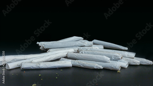 Obraz na płótnie Macro close up of a pile of marijuana joints ranging in size and thickness isolated on black. w salonie