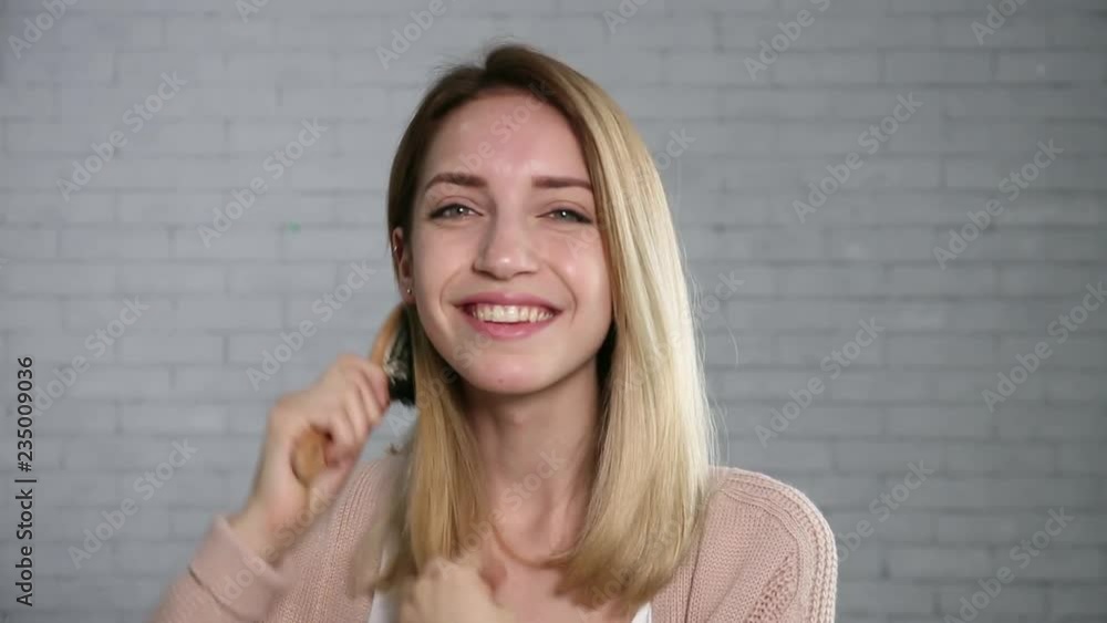 Beautiful young woman brushing hair while looking at camera
Beautiful young woman brushing hair while looking at camera