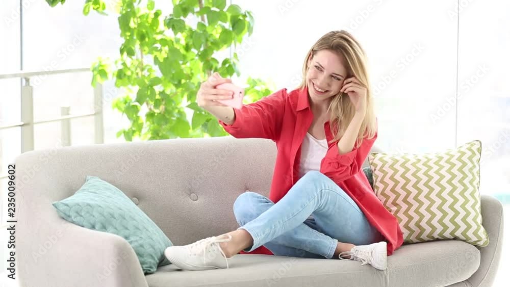 Young woman taking selfie while sitting on sofa at home
