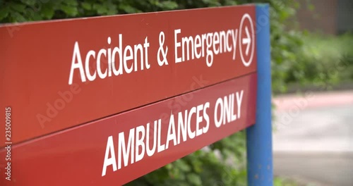 4k Healthcare: hospital sign for accident and emergency department with anonymous family defocussed in the background.
