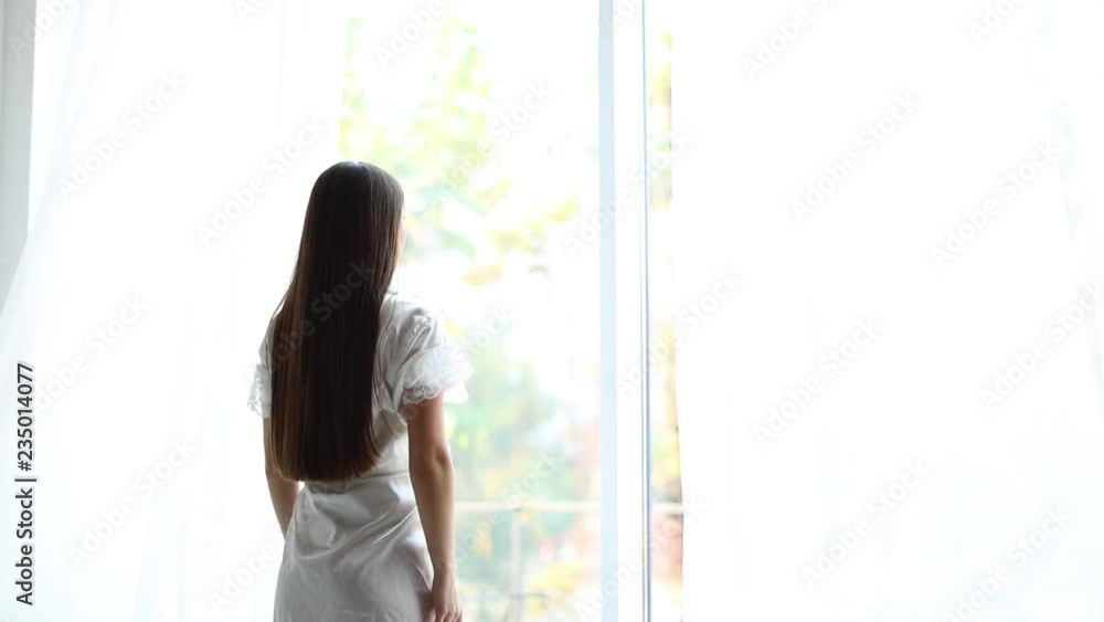 Woman opening curtains at home on beautiful morning
Woman opening curtains at home on beautiful morning