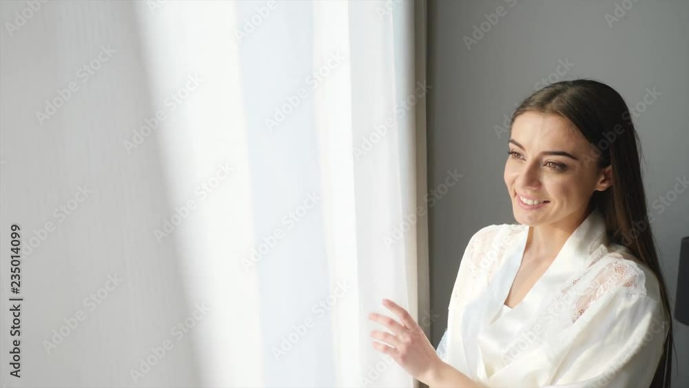 Young woman opening curtains at home on sunny morning
Young woman opening curtains at home on sunny morning