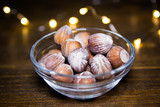 Hazelnuts on bowl on a wooden table with blurred lights in the background