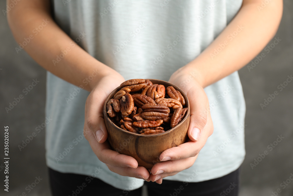 Woman holding bowl with shelled pecan nuts in hands, closeup - obrazy, fototapety, plakaty 