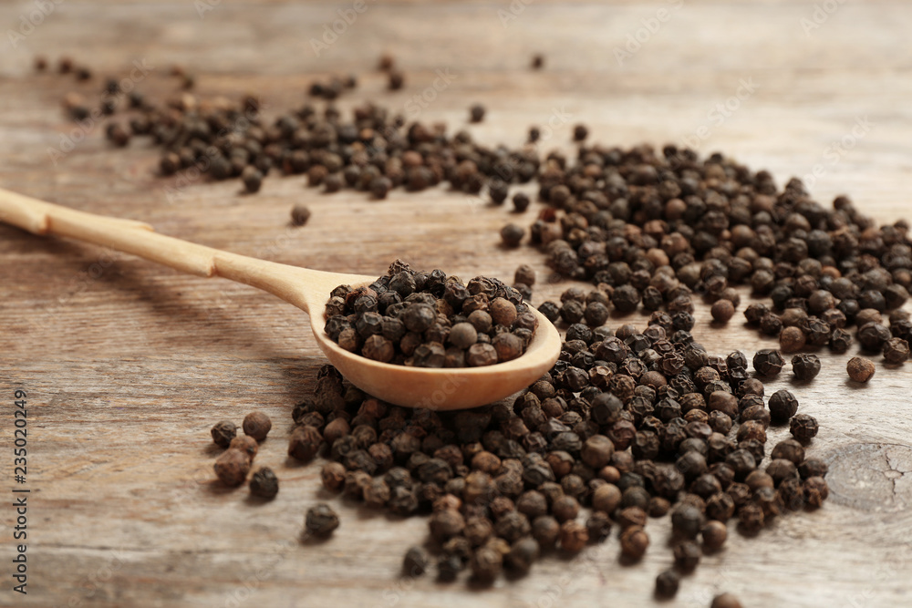Spoon and black peppercorns on wooden table Spoon and black peppercorns on wooden table