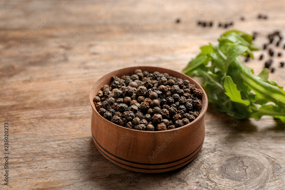 Bowl with black peppercorns on wooden table Bowl with black peppercorns on wooden table