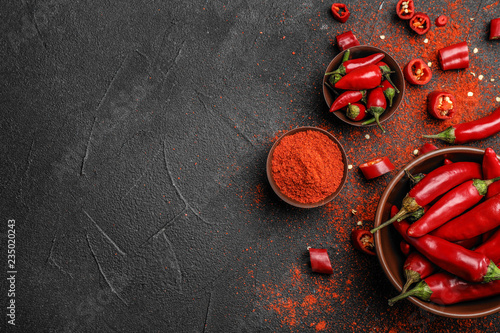 Fotografija Flat lay composition with powdered and raw chili peppers on dark background