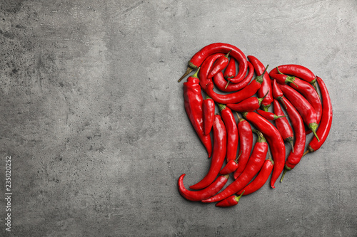 Heart shape made of red chili peppers on gray background, top view with space for text
