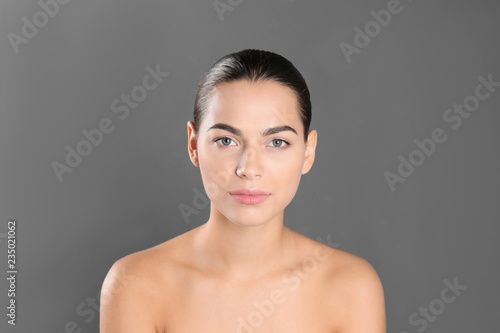 Portrait of beautiful young woman on grey background. Lips contouring, skin care and cosmetic surgery concept
