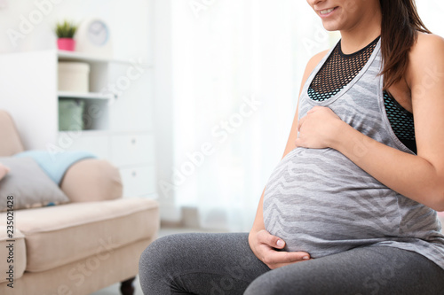 Young pregnant woman in fitness clothes at home, closeup. Space for text © New Africa