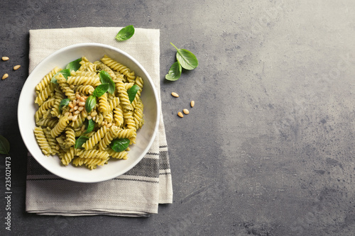 Obraz na płótnie Plate of delicious basil pesto pasta on gray table, top view
