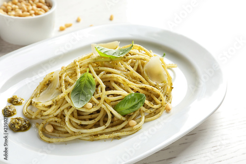 Plate with delicious basil pesto pasta on table