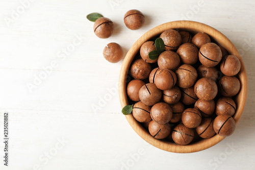 Bowl with organic Macadamia nuts and space for text on white table, top view